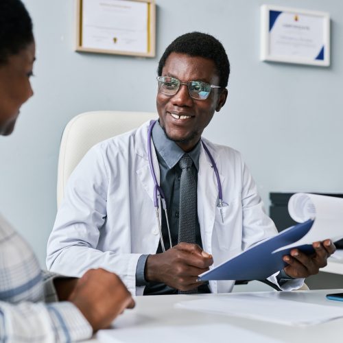 Smiling black doctor consulting female doctor in clinic