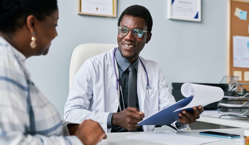 Smiling black doctor consulting female doctor in clinic Smiling black doctor consulting female doctor in clinic